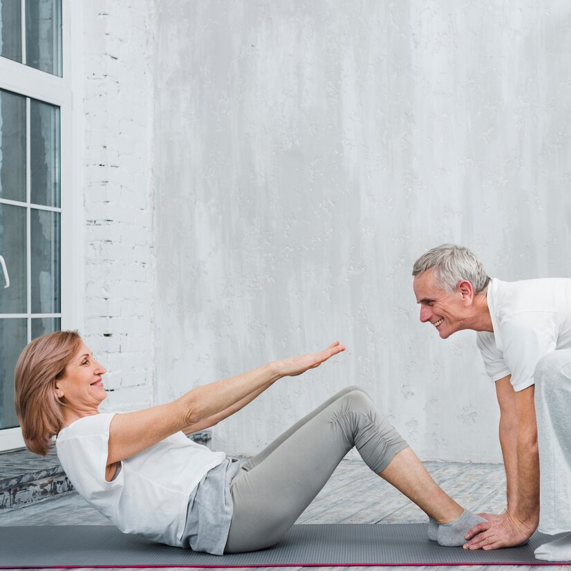 old-woman-with-her-husband-doing-sit-ups-living-room_23-2148097480